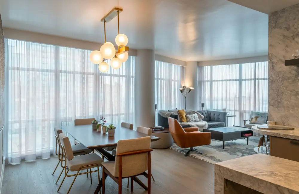 A bright condo living and dining room with floor-to-ceiling sheer curtains