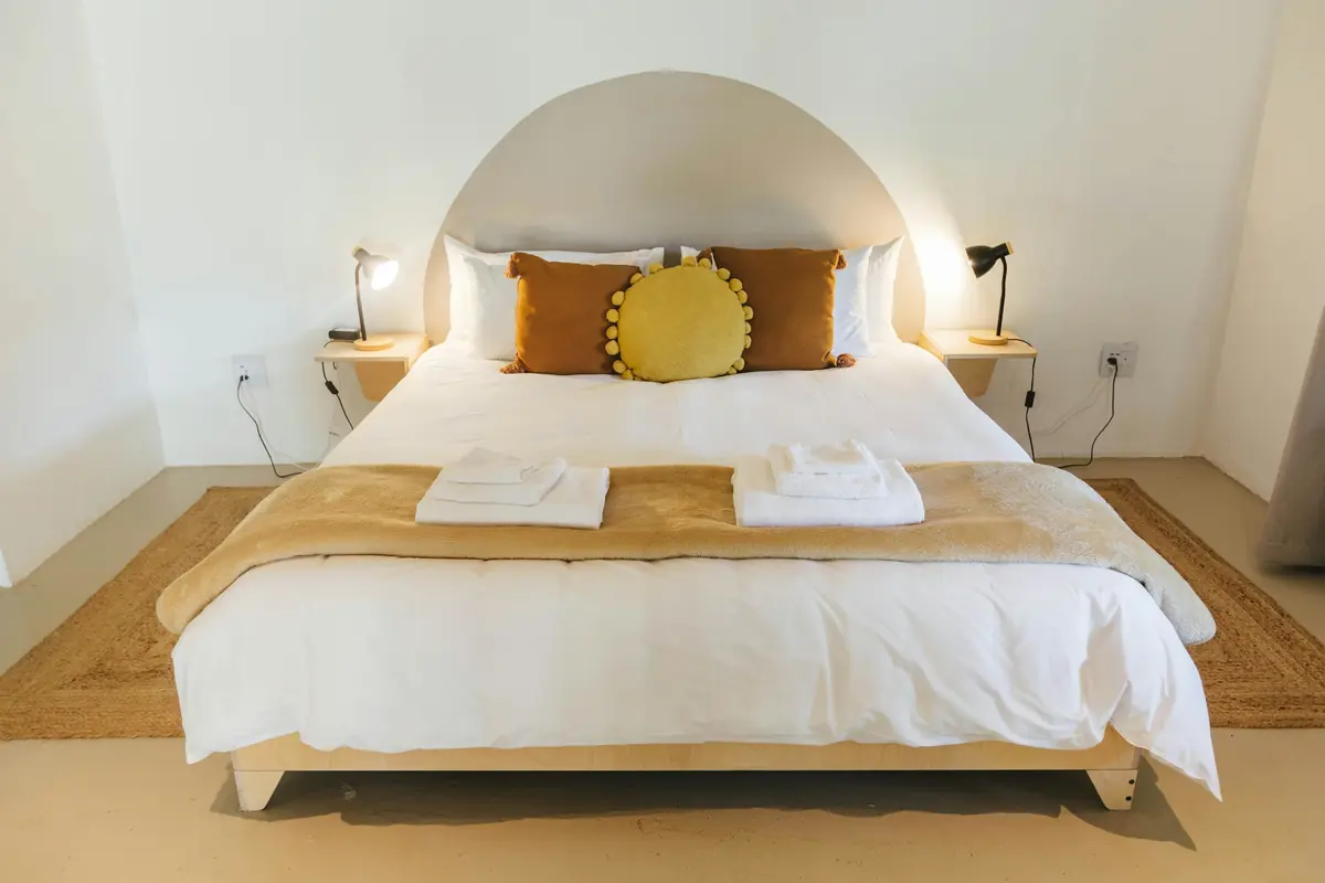 A guest-ready bed with crisp white linens and folded towels